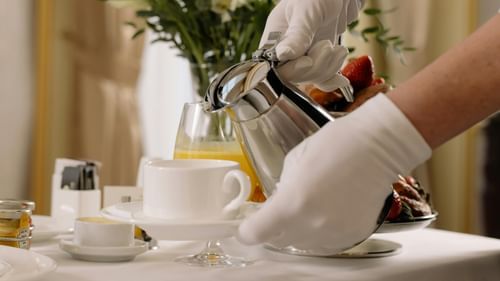 A person pouring coffee into a cup placed on a table
