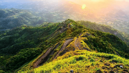 A long, green hillside with a valley at sunrise or sunset.