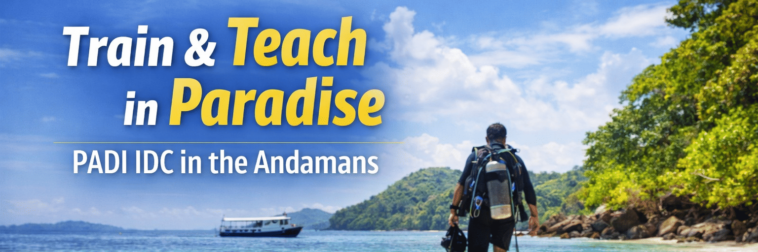 Scuba diver in full gear standing on sandy beach with fins in foreground, turquoise water and green cliffs behind, text promoting PADI IDC training in the Andamans.