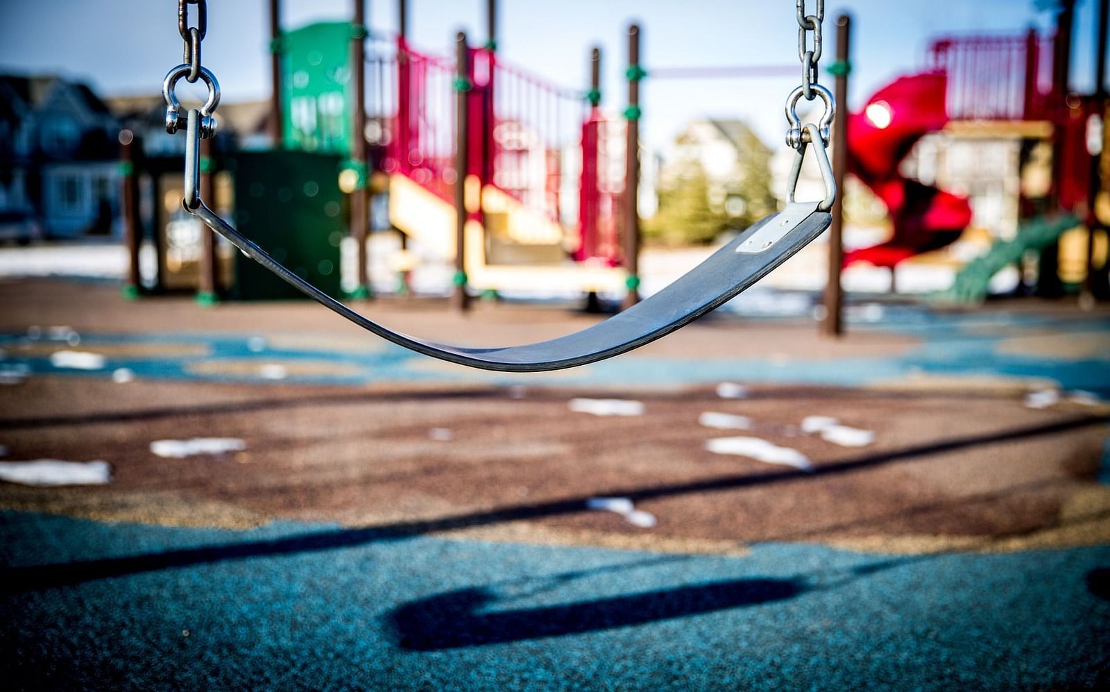A close-up image of a single swing, with the surrounding environment softly blurred. The swing is prominently featured.