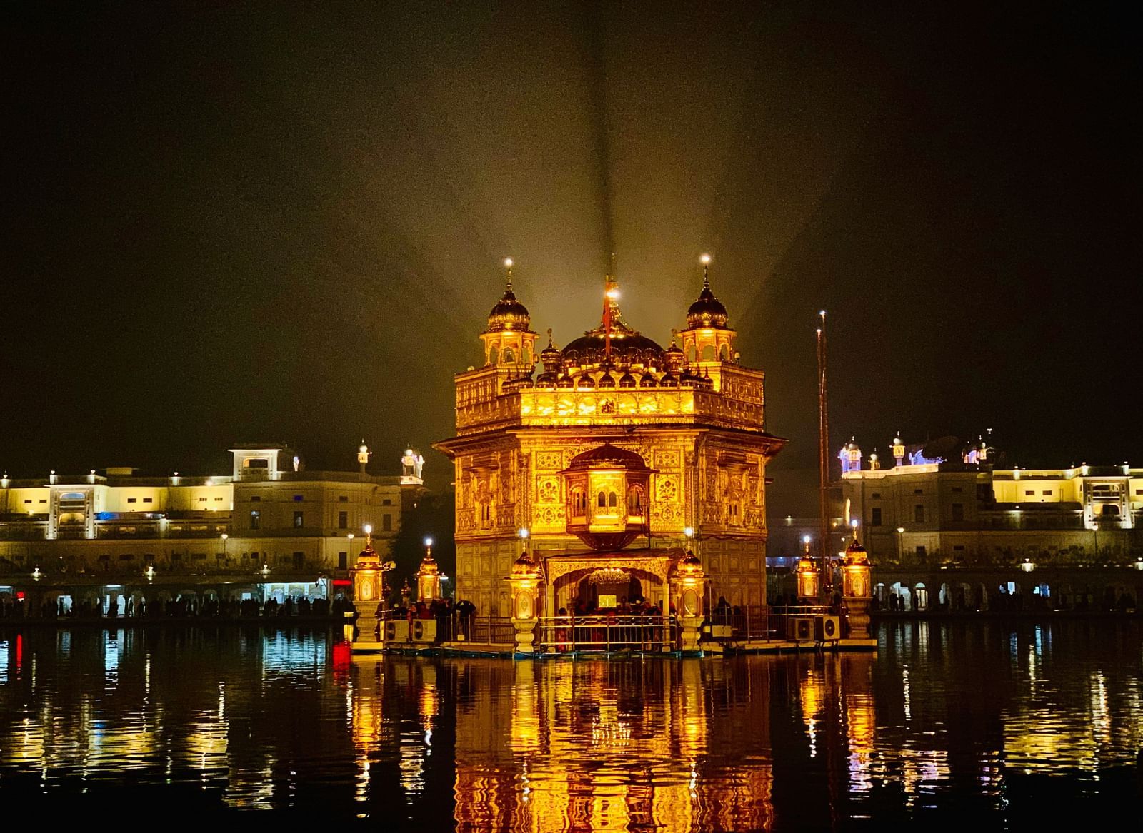 The Golden Temple (Harmandir Sahib) fully illuminated at night, reflecting in the surrounding water.