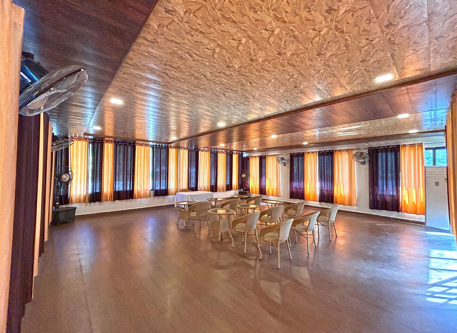 A conference hall with ambient lighting and chairs facing the stage at DLS MJ River Resort, Rishikesh.