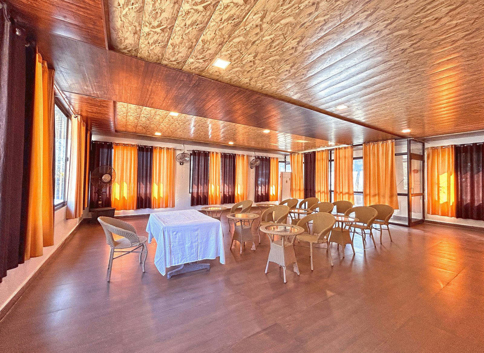 A conference hall with ambient lighting and chairs facing a white table at DLS MJ River Resort, Rishikesh.