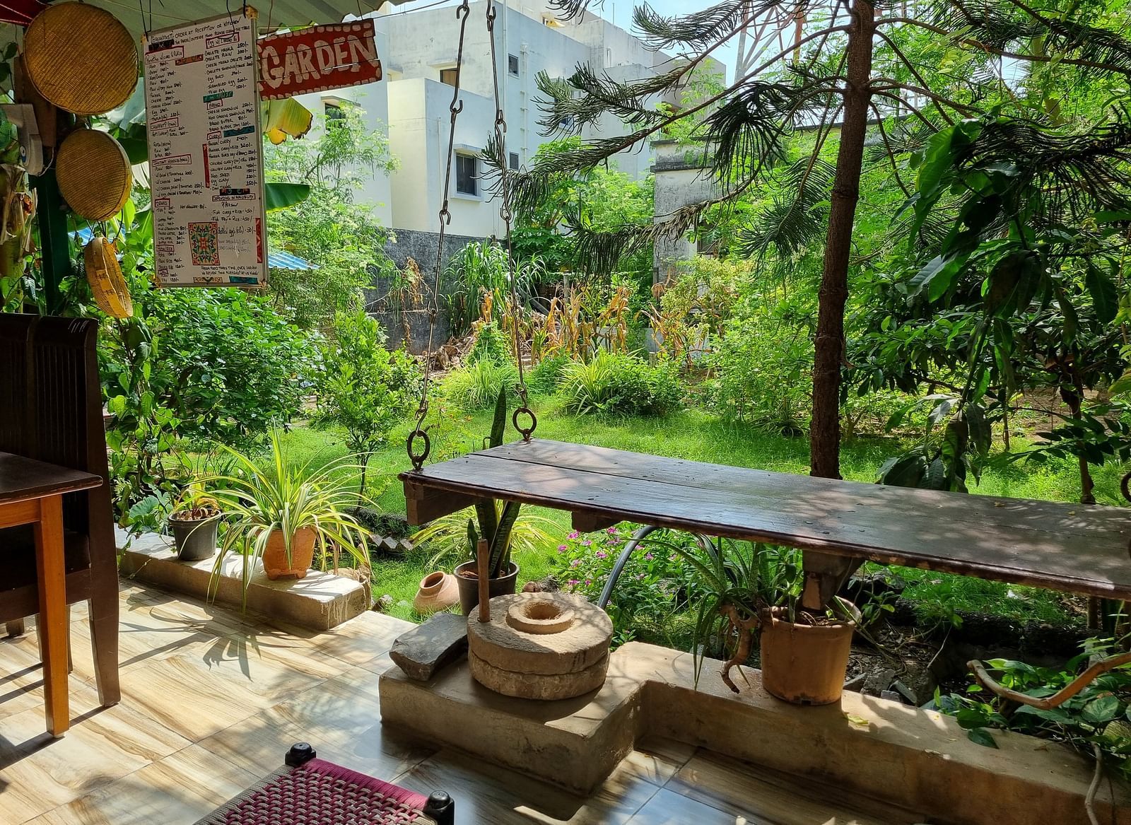 A lush green garden with several bushes and plants at Dream Vision Guest House with a wooden bench overlooking the scenery.