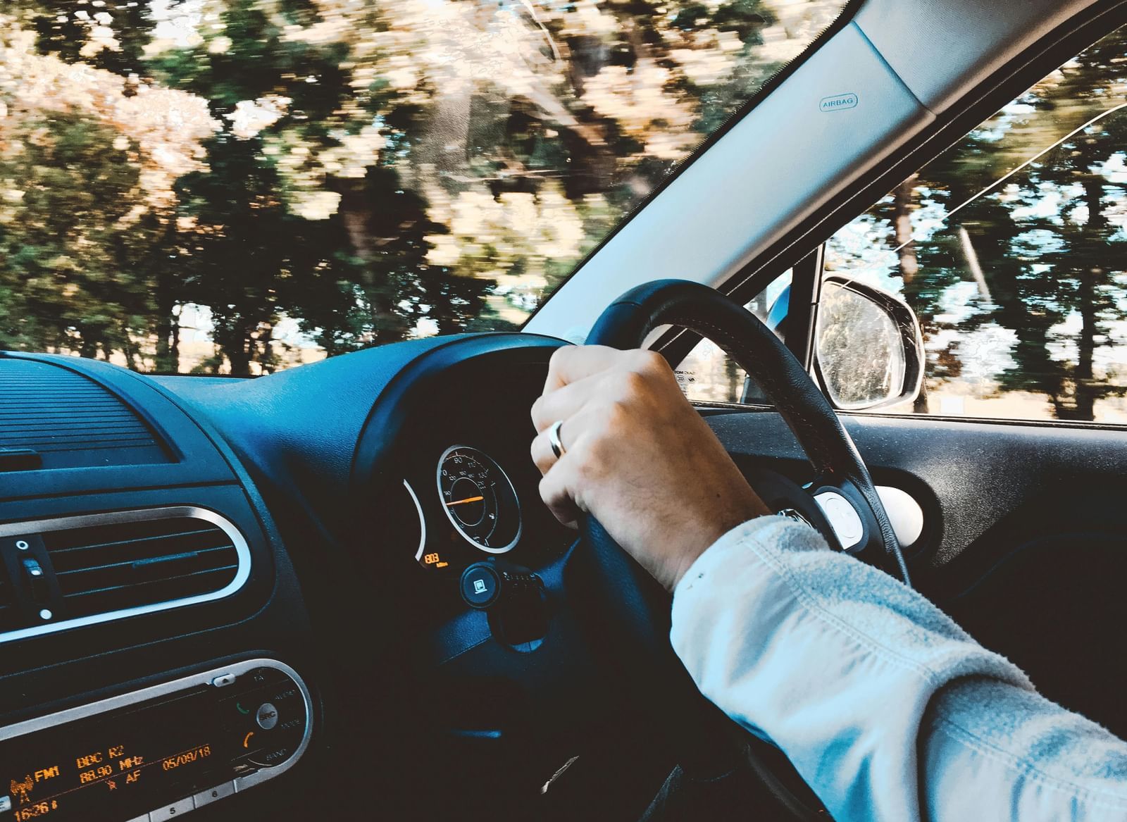 A man driving through a road covered by trees.
