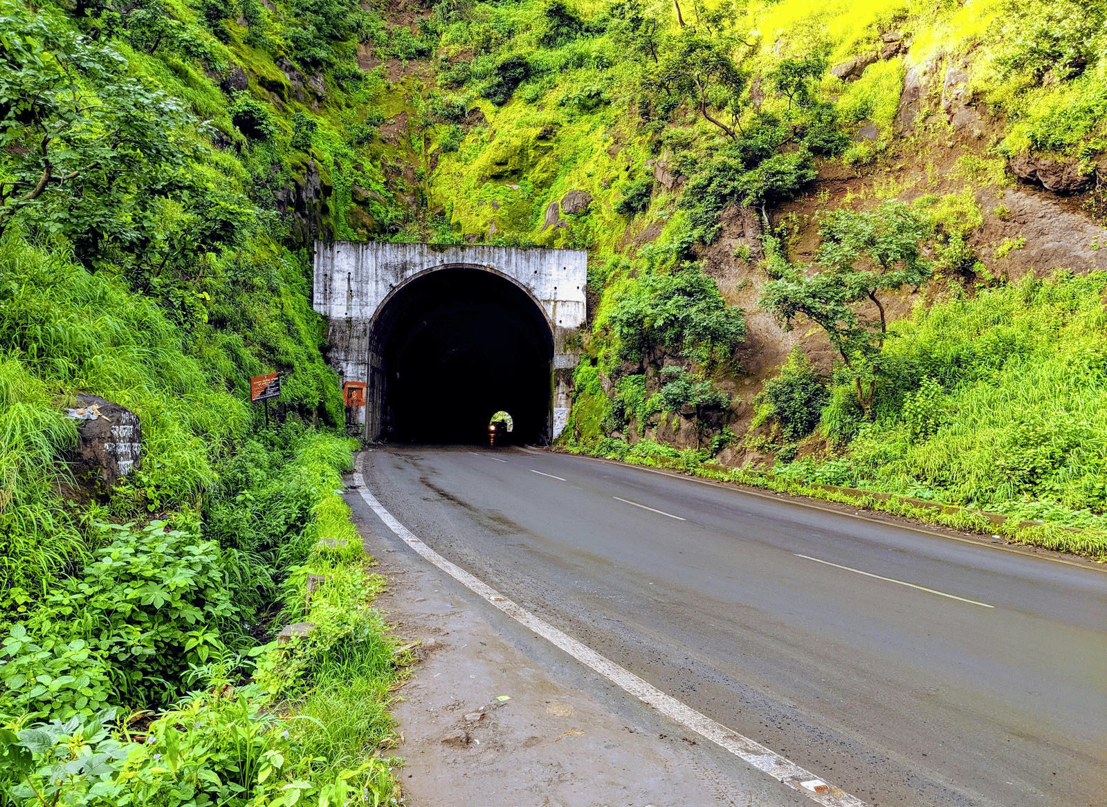 A road leading to a tunnel surrounded by green hills and vegetation.