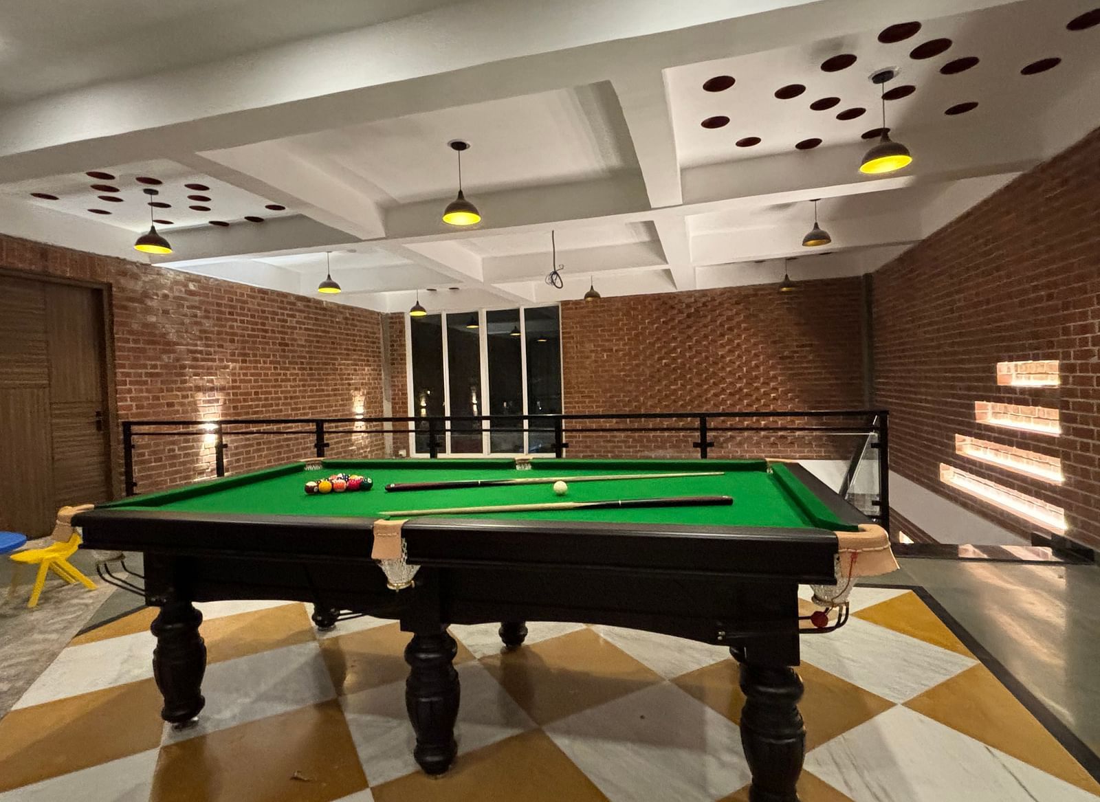 Indoor billiards room with green pool table and modern lighting at Tisya Farms, Gurgaon.