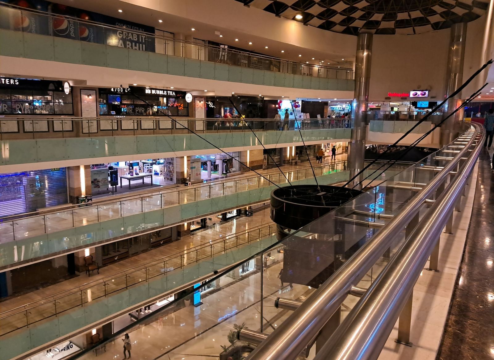 A multi-level shopping mall with brightly lit stores and glass railings.