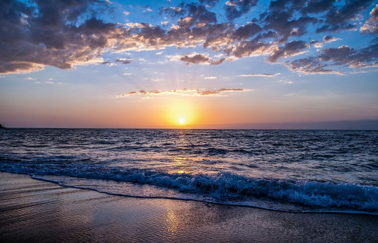 An overview of a beach with the sun setting in the background