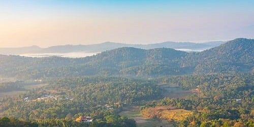 Misty hills with forest and a clear sky.