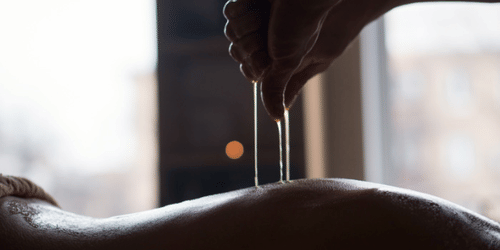 Liquid dropping from a person's hands onto the back of a person