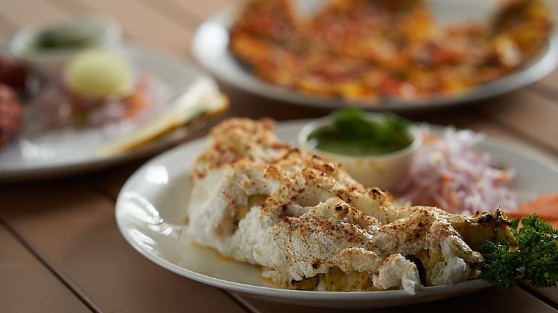A close up shot of an appetiser on a white plate placed on a wooden surface at The Hamuse Hotel, Kodaikanal.