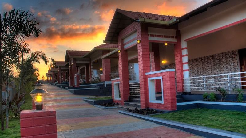Facade of the resort with tiled passage, greenery and sunset | Main Passage | Woodstock Resorts, Coorg