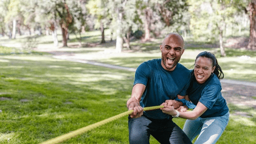 A couple pull a long rope in a grassy park on a sunny day at YO1 Longevity & Health Resorts
