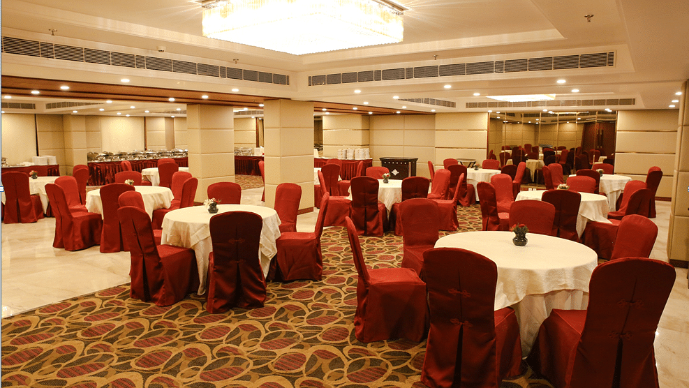 An expansive banquet area with round tables surrounded by red coloured cushioned chairs - Ramada by Wyndham, Ghaziabad, Vasundhara