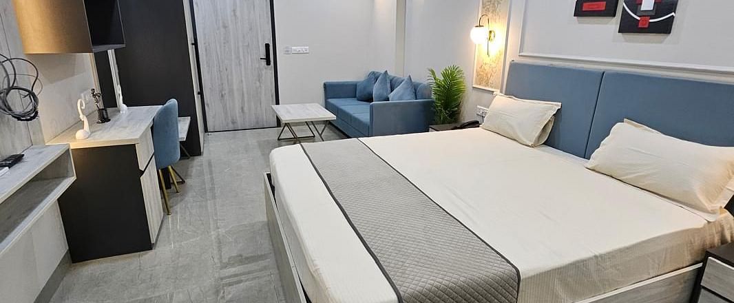 A spacious room with a large bed, side photo frames, and a wall-mounted TV at Urban Suites by BluSalzz, Jaipur.