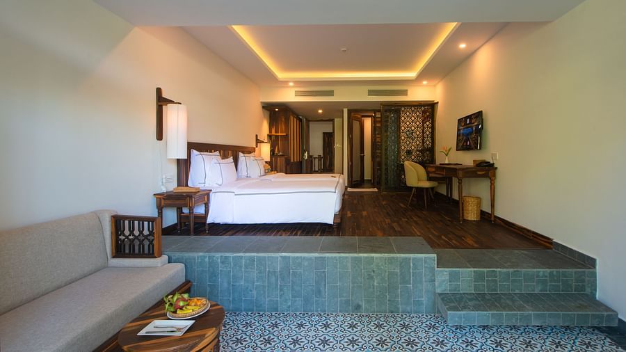 A hotel room with comfortable twin beds, furniture and a wall mounted television on a higher platform - Alibu Resort