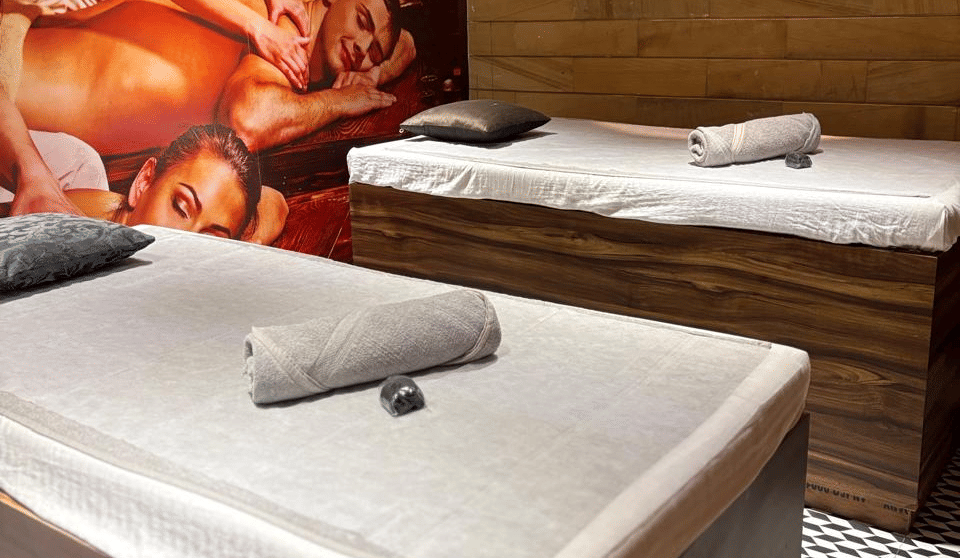 Two SKYN Spa treatment beds with rolled towels beside a massage mural and wood-panelled wall