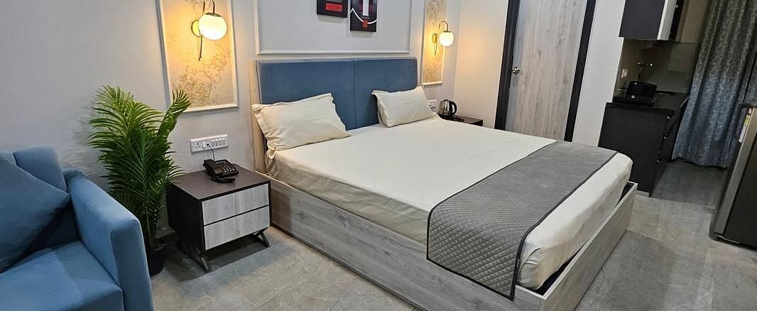 Diagonal view of a spacious room with a large bed, bedside lamps on both sides, and the bedroom at Urban Suites by BluSalzz, Jaipur.