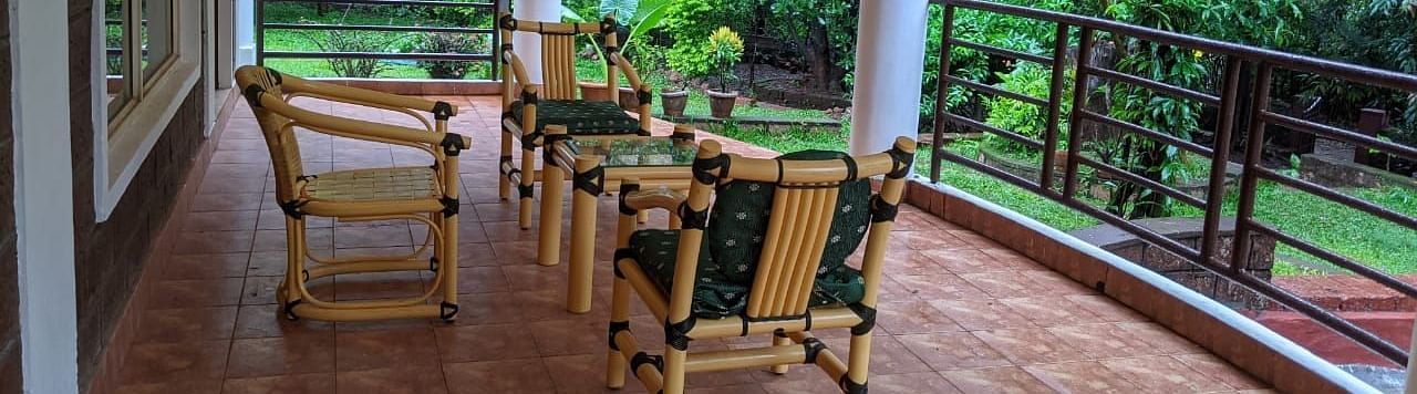 An outdoor seating area with ratan chairs and view of the surrounding greenery at The Conservancy Bungalow.