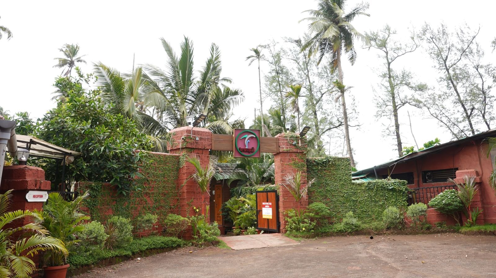 Entrance to a tropical resort with a brick archway and lush greenery - Tranquil Beach Resort, Harihareshwar