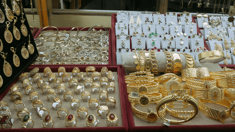 A close-up shot of a display case filled with a variety of gold and silver jewellery, including bangles and bracelets at Souq Waqif Gold Market.