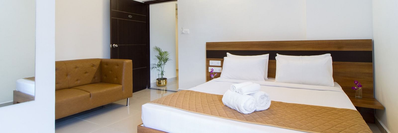 A hotel room including a double bed with bedding and an armchair at Sanctum Suites Whitefield, Bangalore.