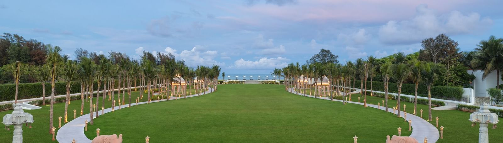 A view of our gigantic outdoor lawn surrounded by lush greenery and a blue sky with pinkish hues in the background – Kaldan Samudra Palace, Mahabalipuram, one of the finest Marriage Lawns in ECR