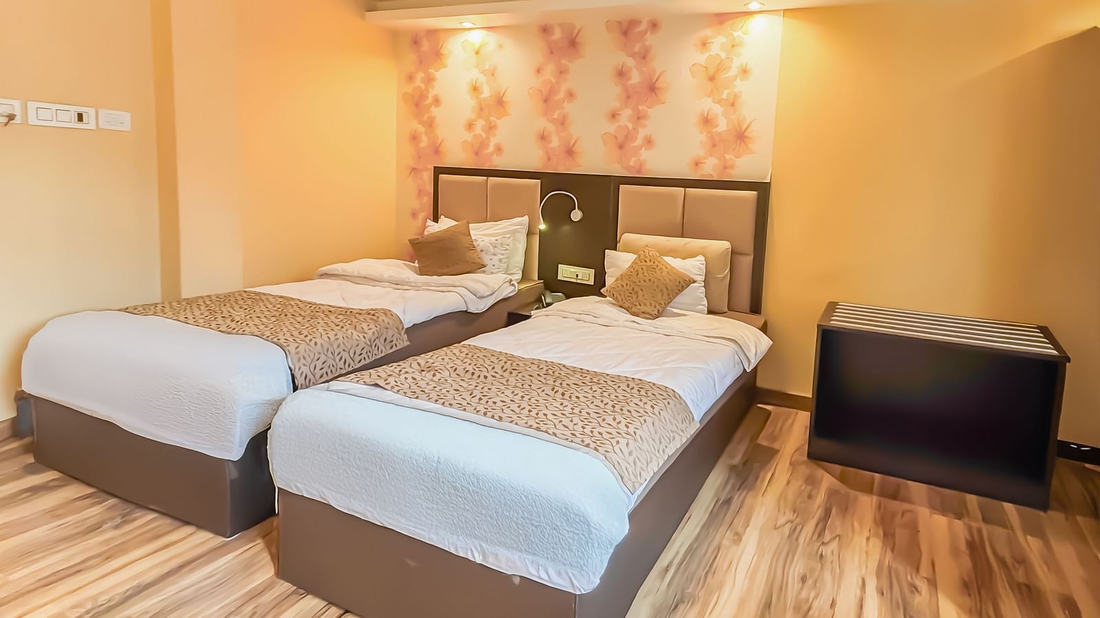 Twin beds with a decorative painting behind the headboard at Avianna Hungry Jack, Gangtok.