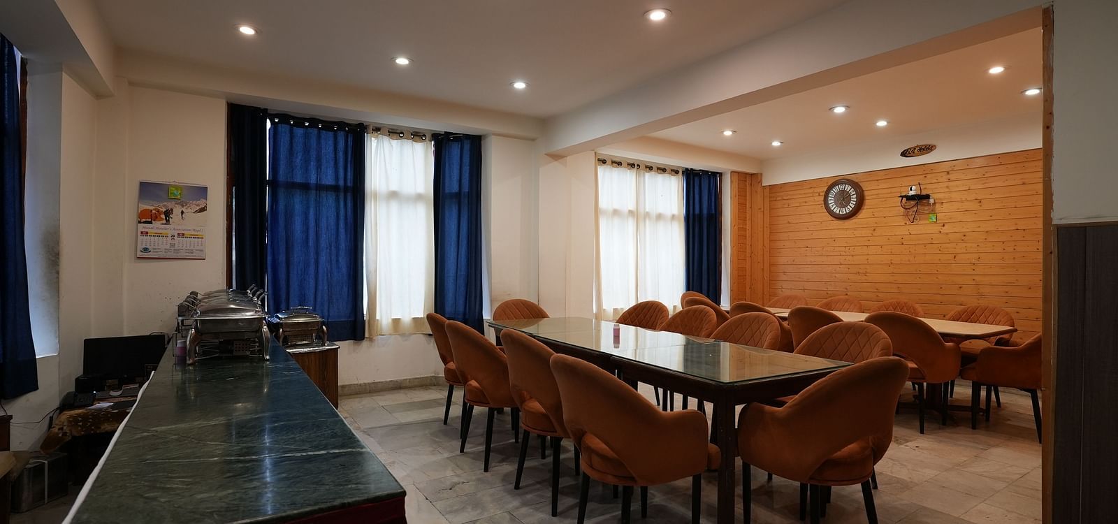 Spacious hotel conference or dining room with long tables, chairs, and bright lighting, suitable for meetings or group dining.