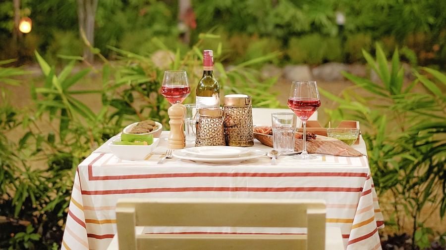 A close-up view of a beautifully set dining table at Neer Ganga, featuring a neatly arranged tablecloth, elegant cutlery, wine glasses, and a bottle of wine, creating an inviting and refined dining atmosphere.