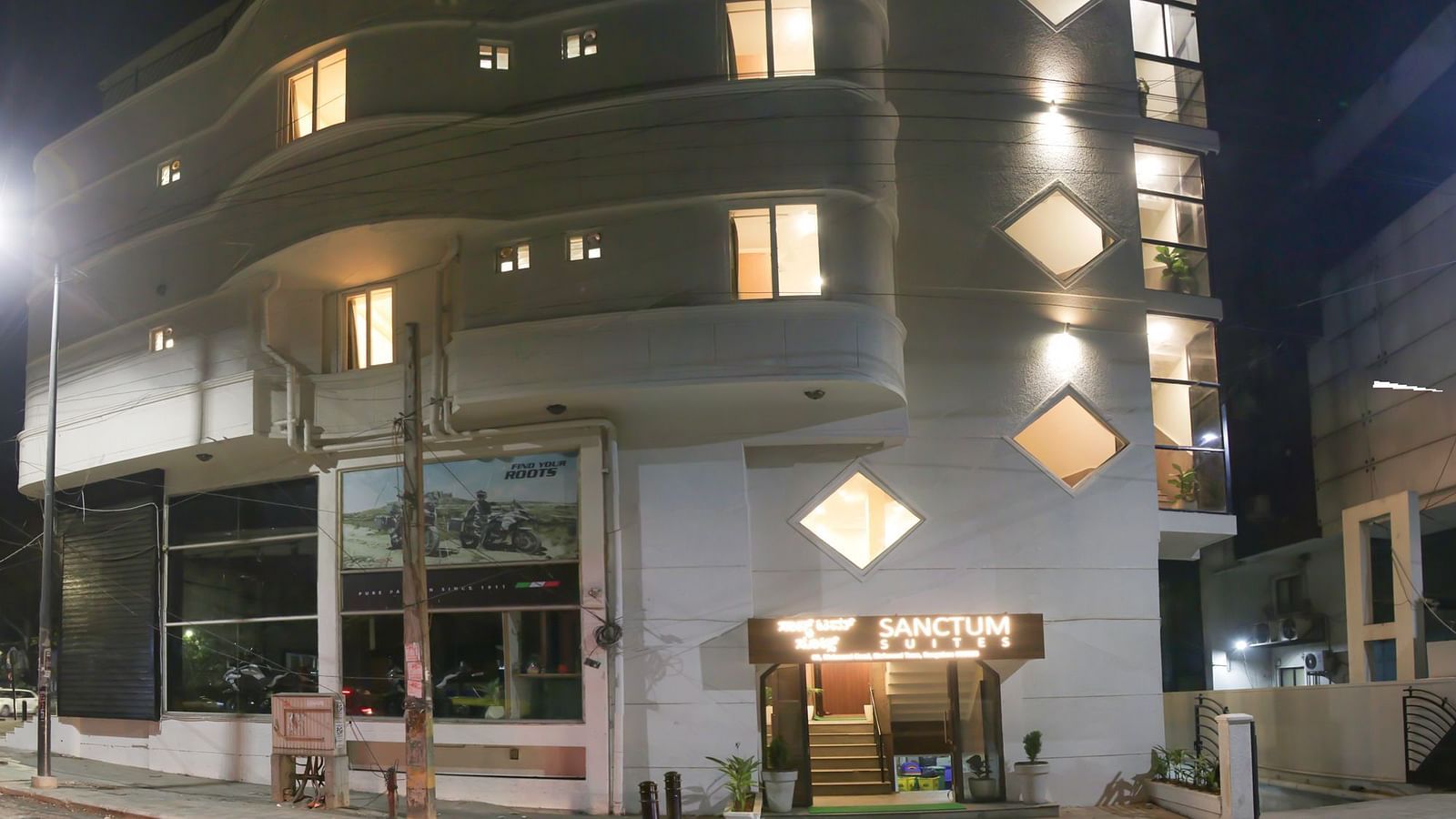 An exterior view of a building with warm lighting which is shot at night - Sanctum Suites Richmond Road, Bangalore