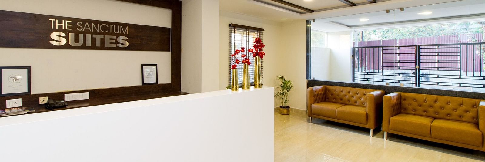 A hotel reception area featuring a white desk and two sofas at Sanctum Suites Whitefield, Bangalore.