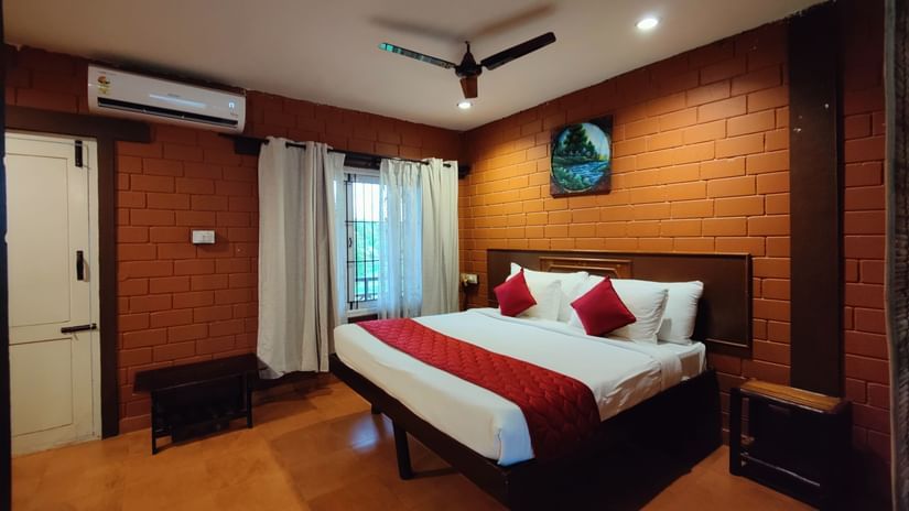 Executive Deluxe Room under warm lighting with a wall art over the headboard and a window next to it at Ibex River Resort, Pollachi