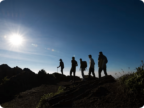 A group of people walking on a trail of the Mullayanagari Hike with their silhouette in view - The Serai, Chikmagalur.