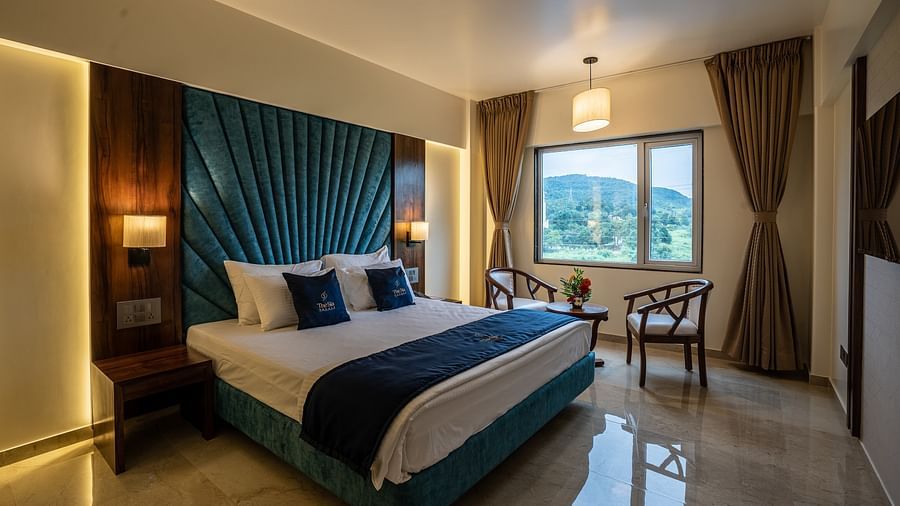 View of Suite with king sized bed and bedside tables seating area with windows and curtains - Mastiff Grand - The Sia Palace Suites Banquets Khopoli