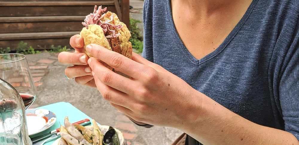 A woman with a  type of food in her hands, smiling.