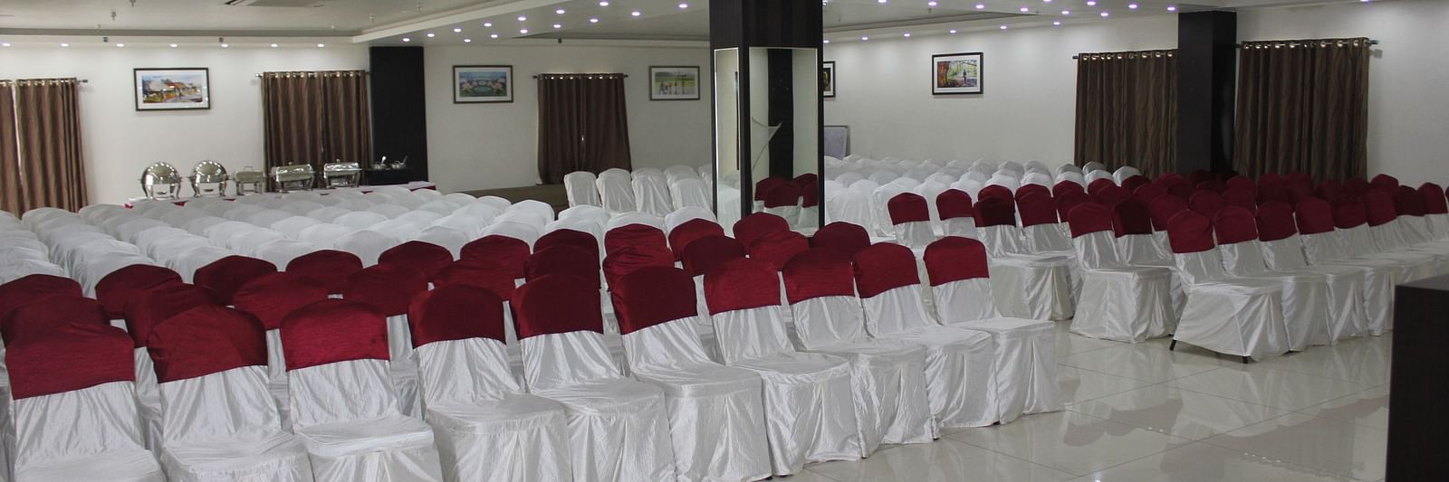 Jyothi hall with seats arranged and lights on the ceiling at Hotel Green Apple