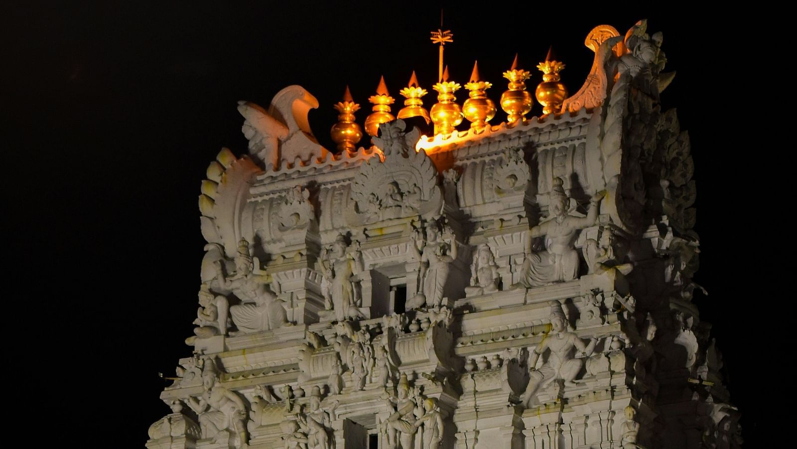 An overview of the facade of a temple in Tirupati with lights shining on it