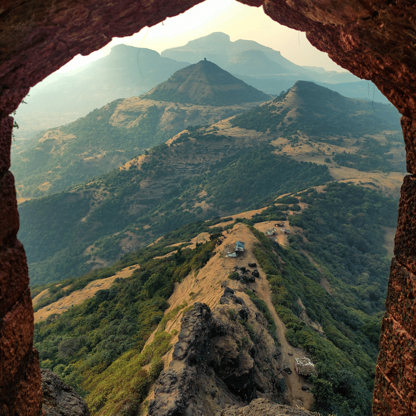Scenic view of a winding mountain road through a lush, foggy valley.