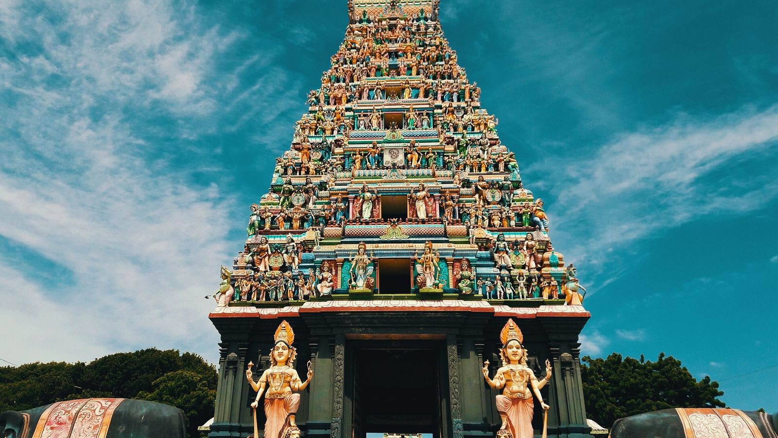 A temple with intricate carvings on its roof and two hindu deities on either side of the entrance