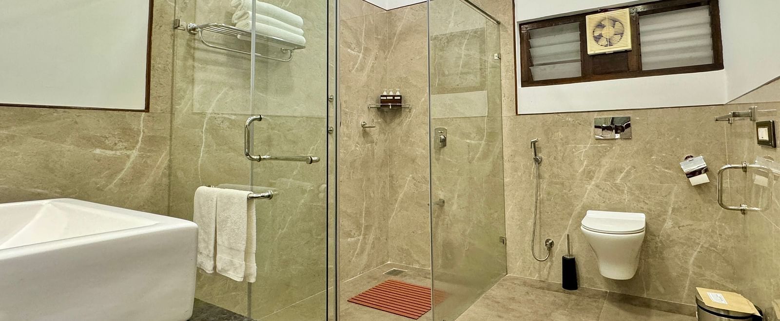 Modern bathroom with a glass shower enclosure, toilet, and tiled walls - BluSalzz Collection - Tranquil Resort, Wayanad