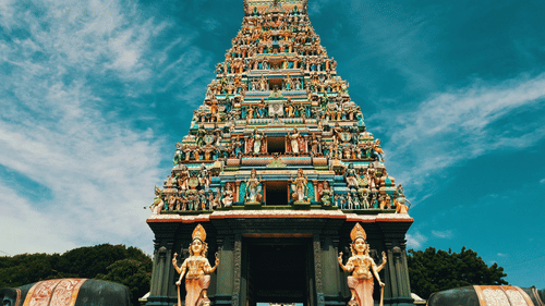 facade image of a temple with intricate carvings of deities on the roof