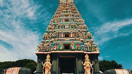 A temple with intricate carvings on its roof and two hindu deities on either side of the entrance.