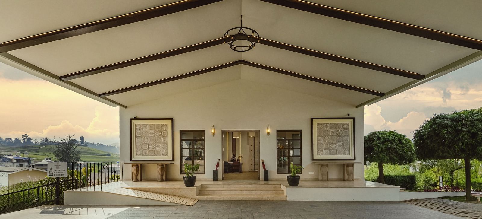Covered outdoor veranda at Mango Hill Shola, Ooty, with tall pillars, arched doorways, and views of the natural landscape beyond.