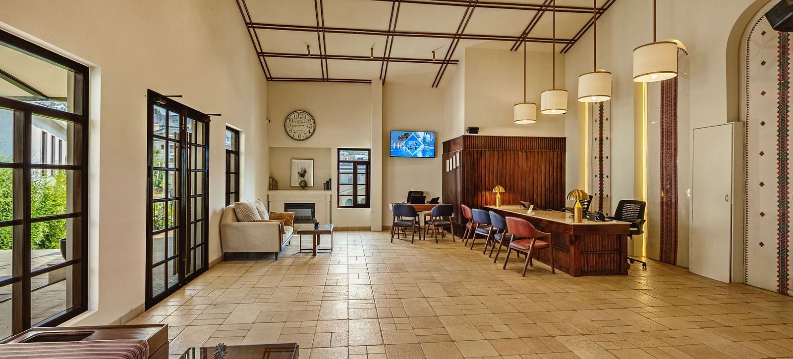Bright interior hallway at Mango Hill Shola, Ooty, with tiled floors, wide windows allowing natural light, and casual seating arrangements along the corridor.