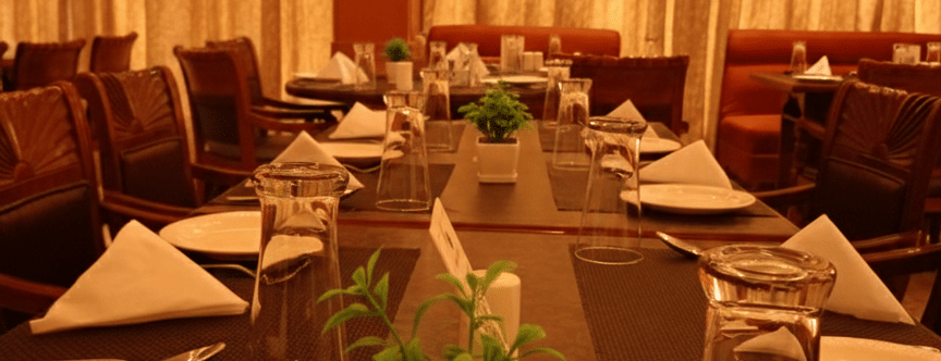 Table setup at Hotel Gold, Panipat with plates, glasses, cutlery, and decor arranged for dining.