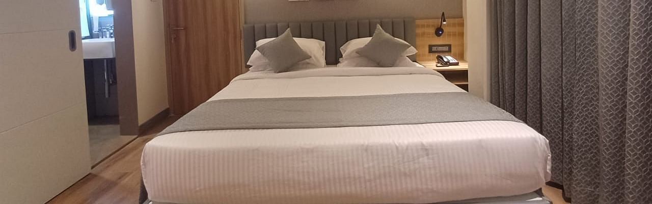 Image of a room wuth double bed and a door on the side of the bed at Hotel Raai, Hosur.