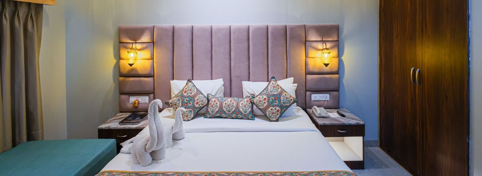 Double bed at Bamboo Saa Resort & Spa, Udaipur with upholstered headboard and towel figurines.