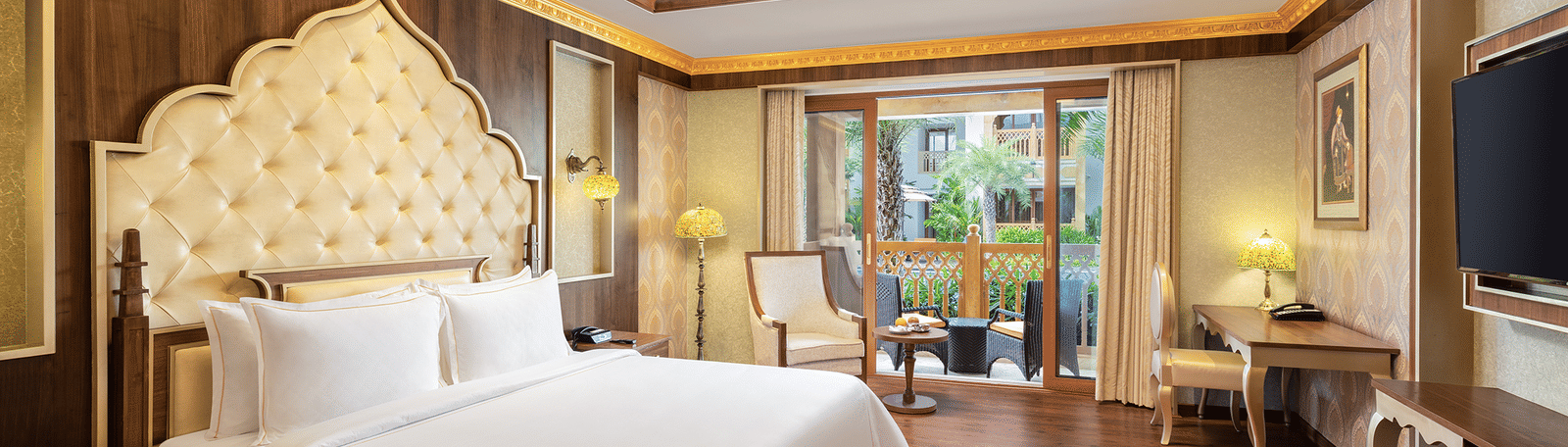 A hotel room in Mahabalipuram with rich wooden flooring, a large bed, and comfortable seating arrangement – Kaldan Samudra, one of the finest Mahabalipuram beach resorts